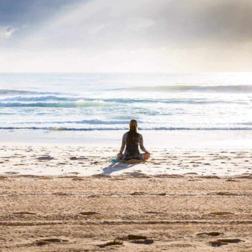 Photo of woman meditating on beach
